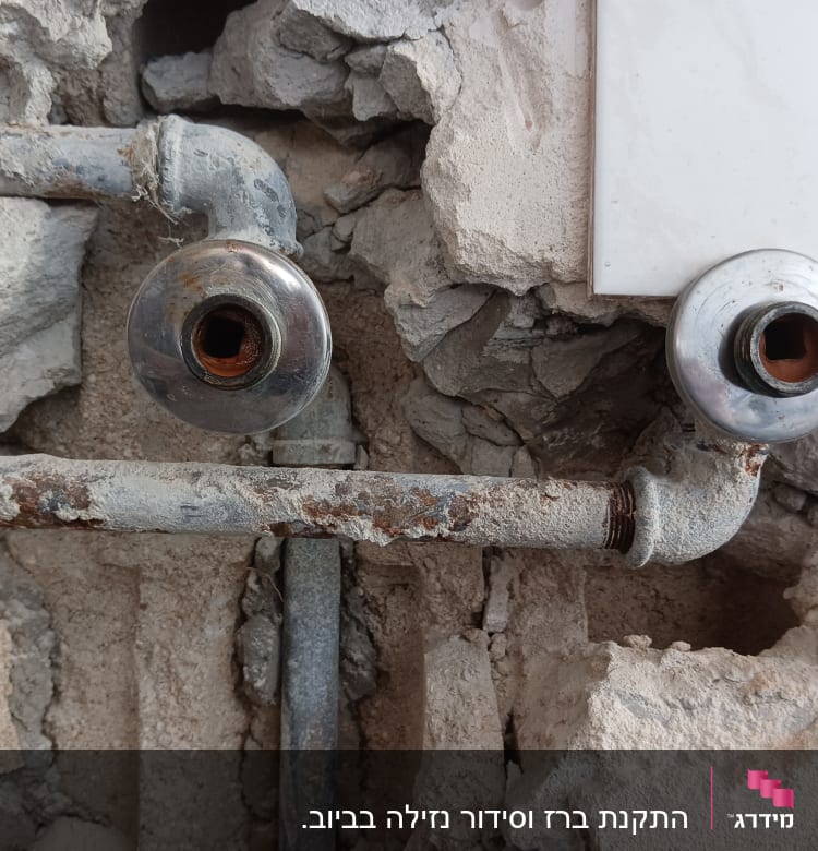 צינורות חלודים בקיר עם חיבורים מתכתיים